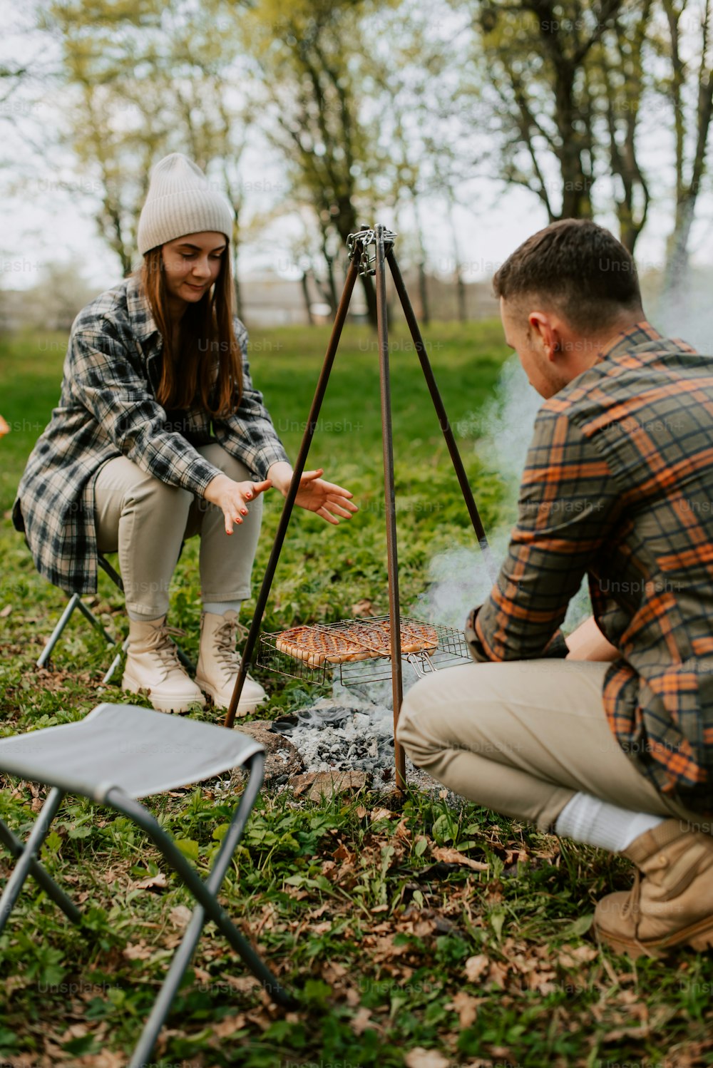 a man and a woman sitting next to a campfire