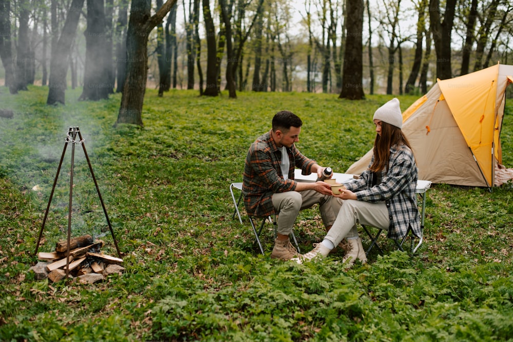 a man and a woman sitting next to a tent