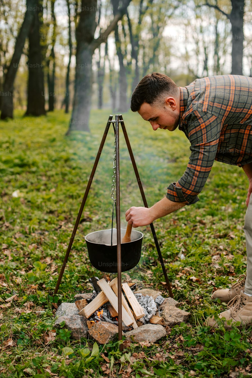 a man cooking food over an open fire in the woods