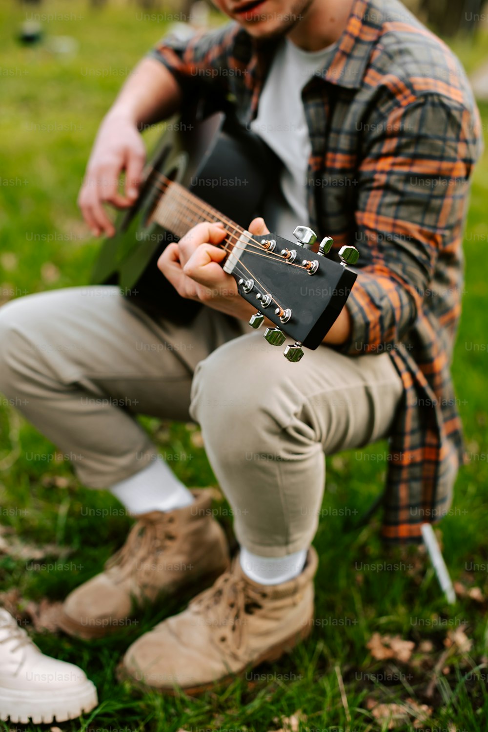 a man sitting in the grass playing a guitar