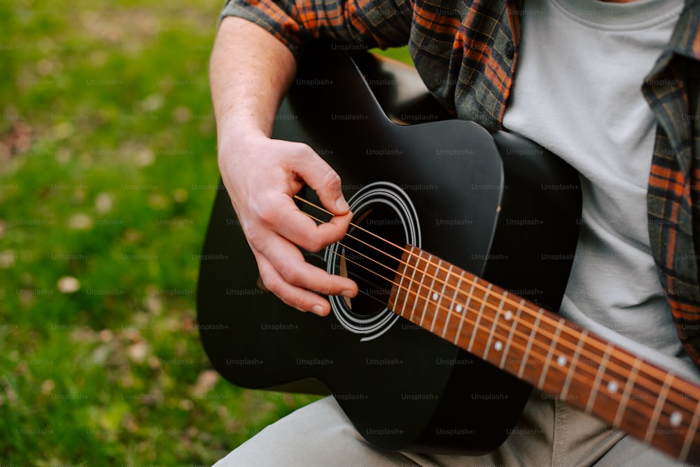 a man is playing a guitar outside in the grass