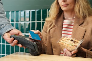 Una mujer pagando a un hombre una tarjeta de crédito