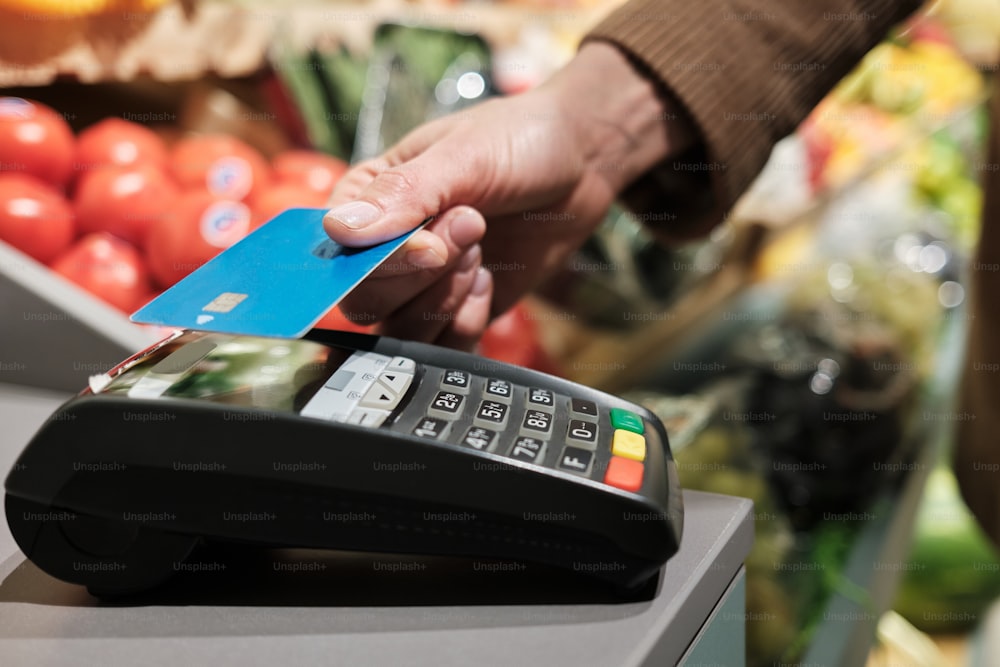 a person holding a credit card in front of a cash register