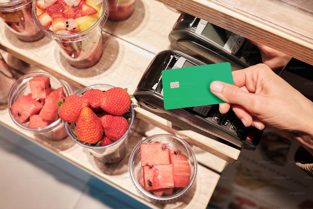 a person holding a green card in front of some fruit