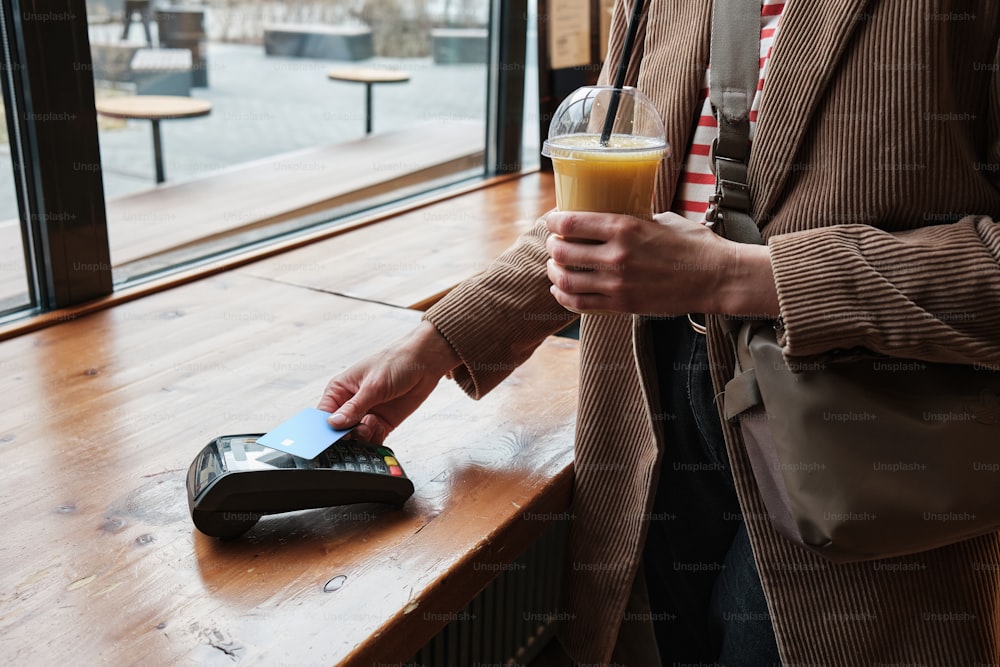 a person holding a drink and a cell phone