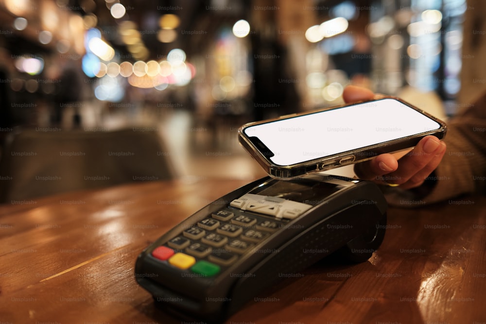 a person holding a cell phone over a payphone