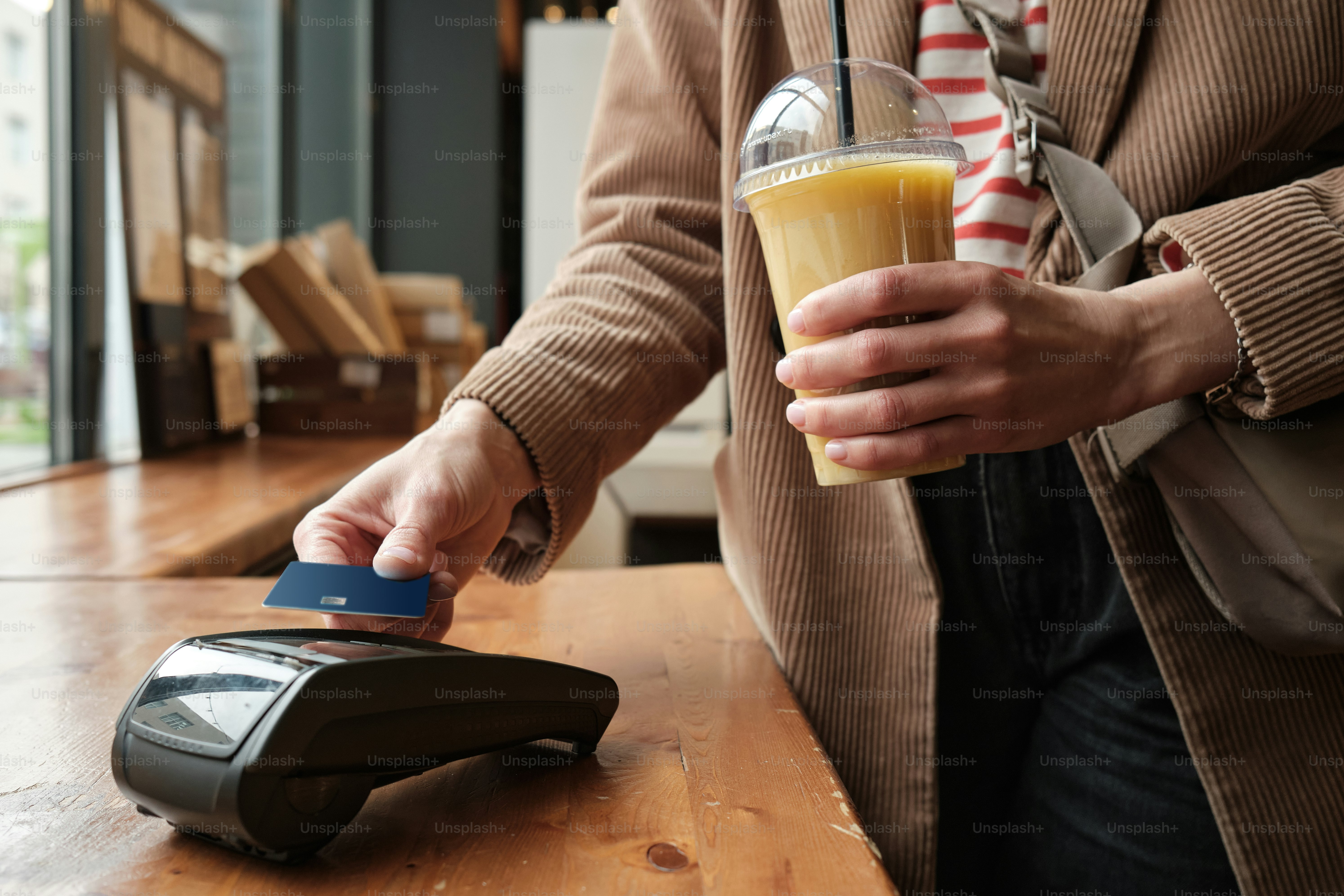 una persona sosteniendo una bebida y un teléfono celular