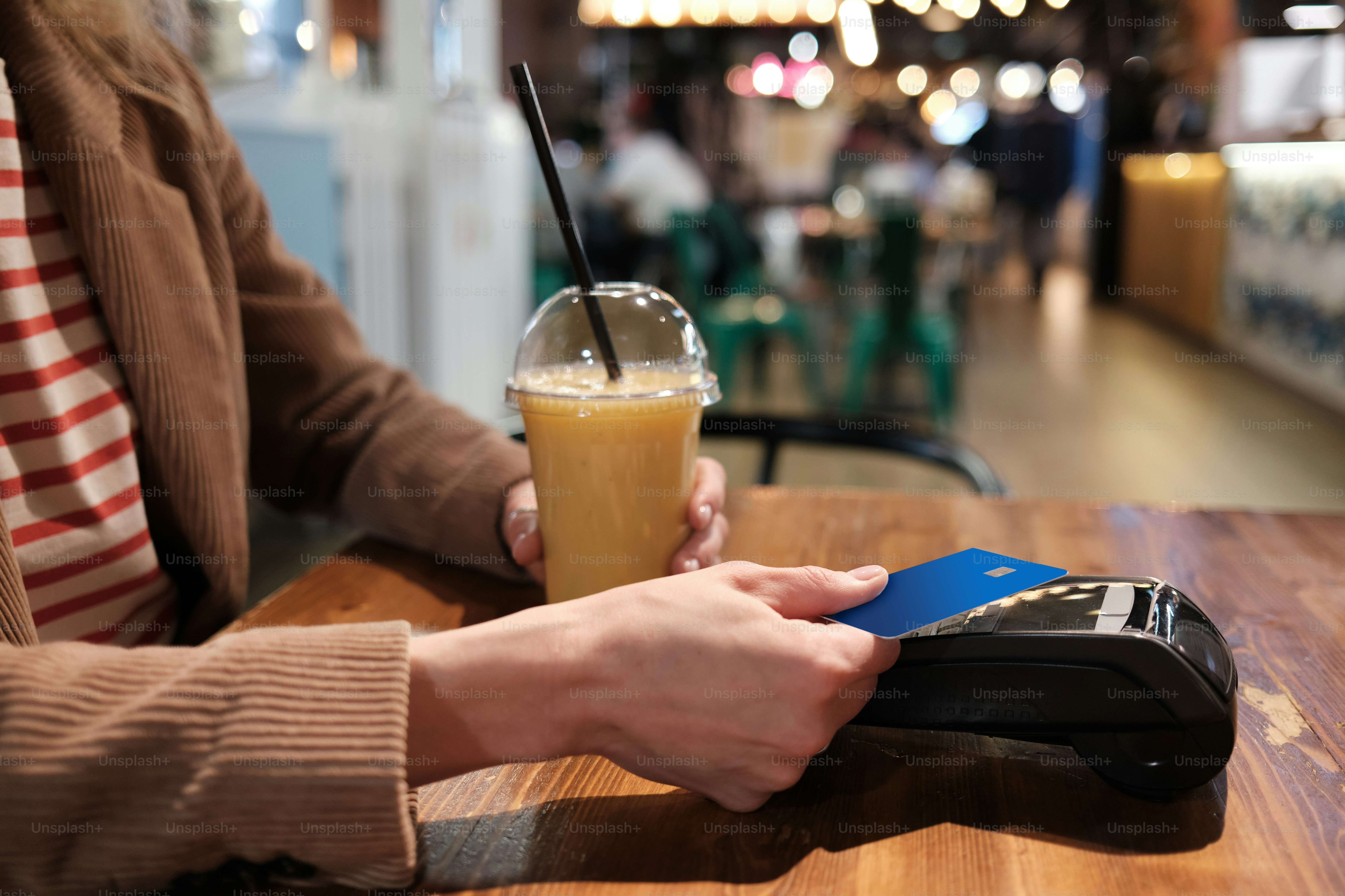 a person sitting at a table with a cell phone and a drink