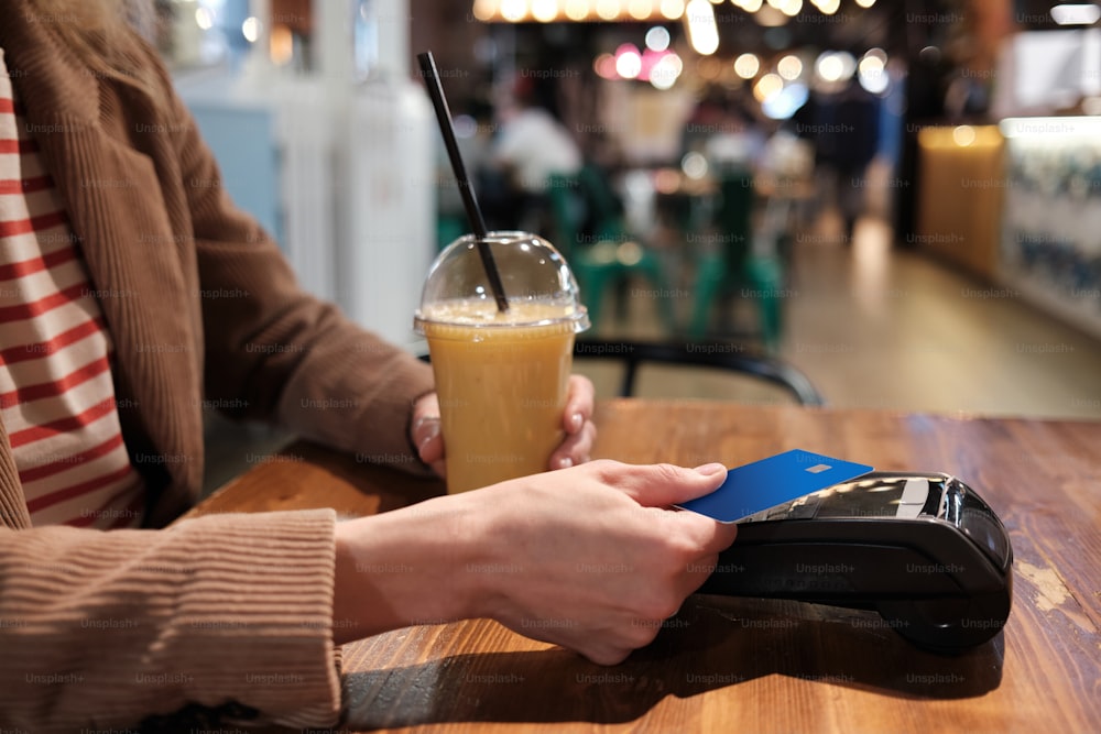 une personne assise à une table avec un téléphone cellulaire et une boisson