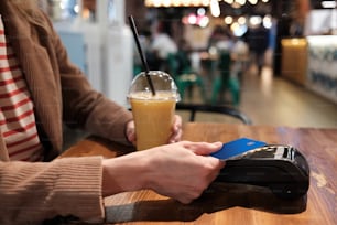 Una persona sentada en una mesa con un teléfono celular y una bebida