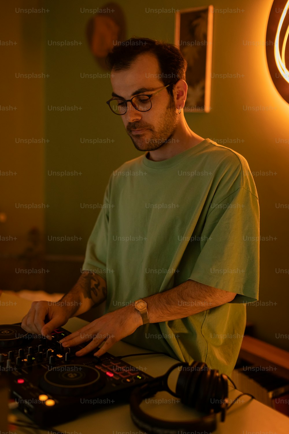 um homem em uma camisa verde usando um controlador dj