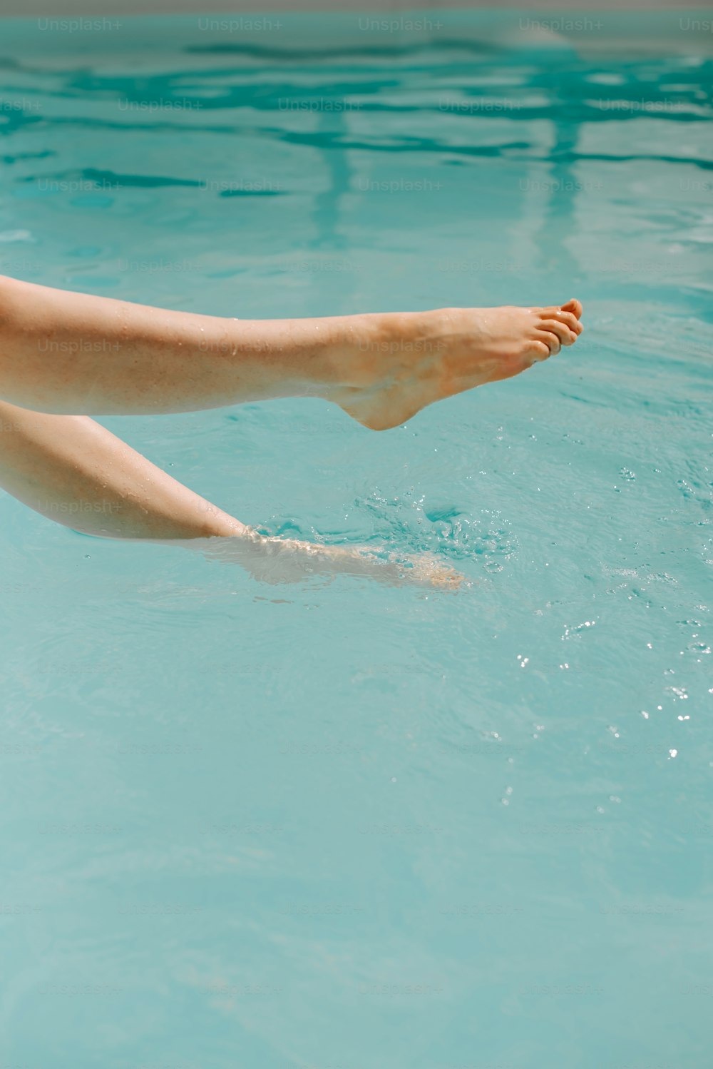 os pés descalços de uma mulher flutuando em uma piscina de água