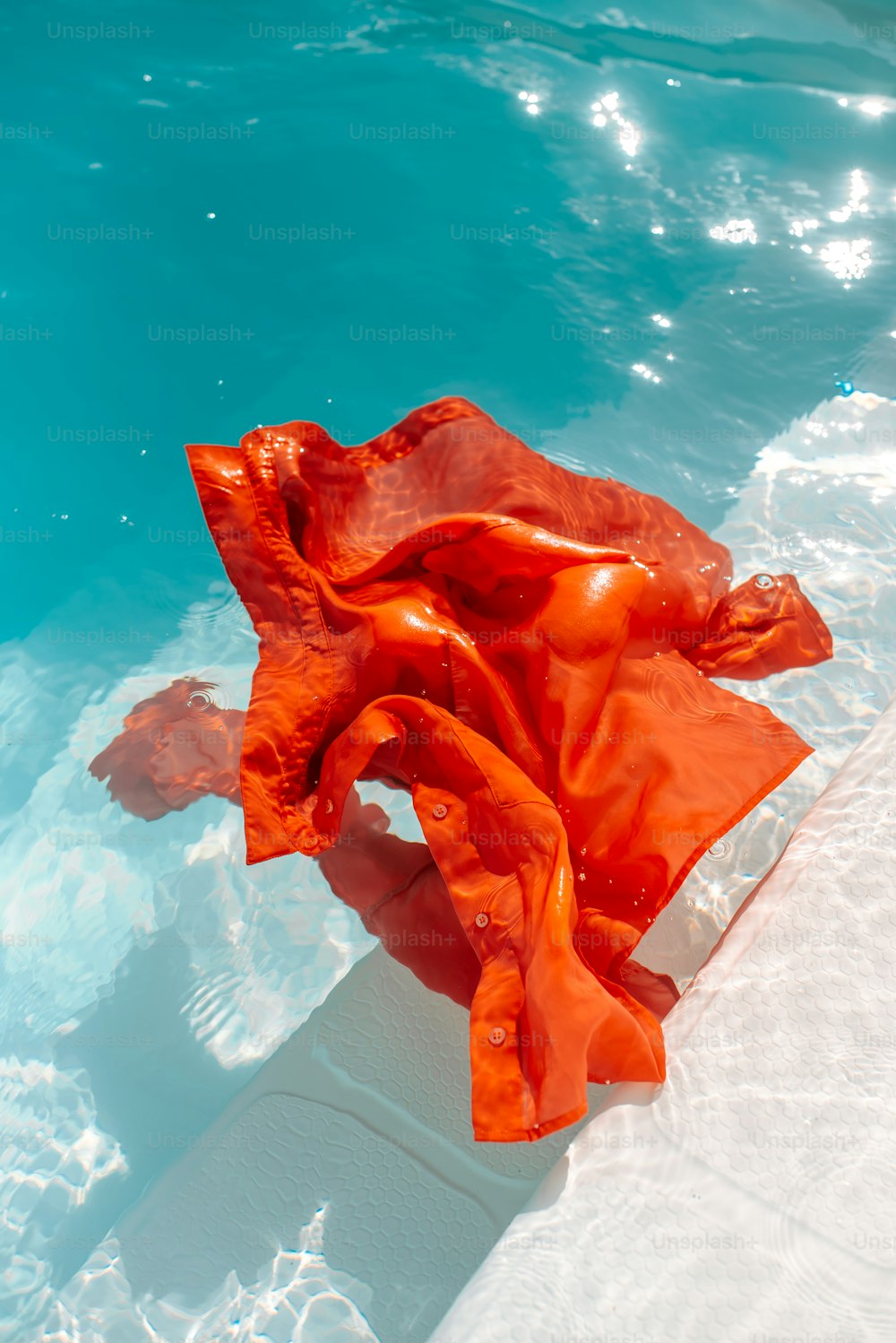 an orange cloth floating in a pool of water