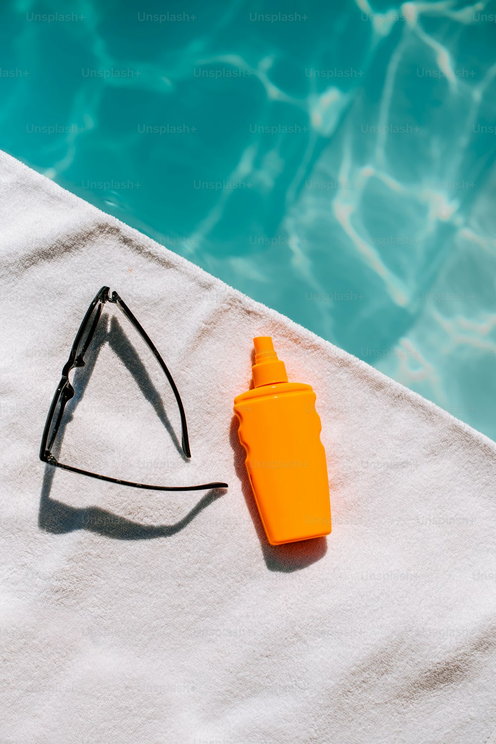 Una botella de protector solar junto a un par de gafas de sol