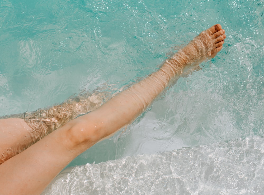 une femme allongée dans l’eau, les pieds dans l’eau