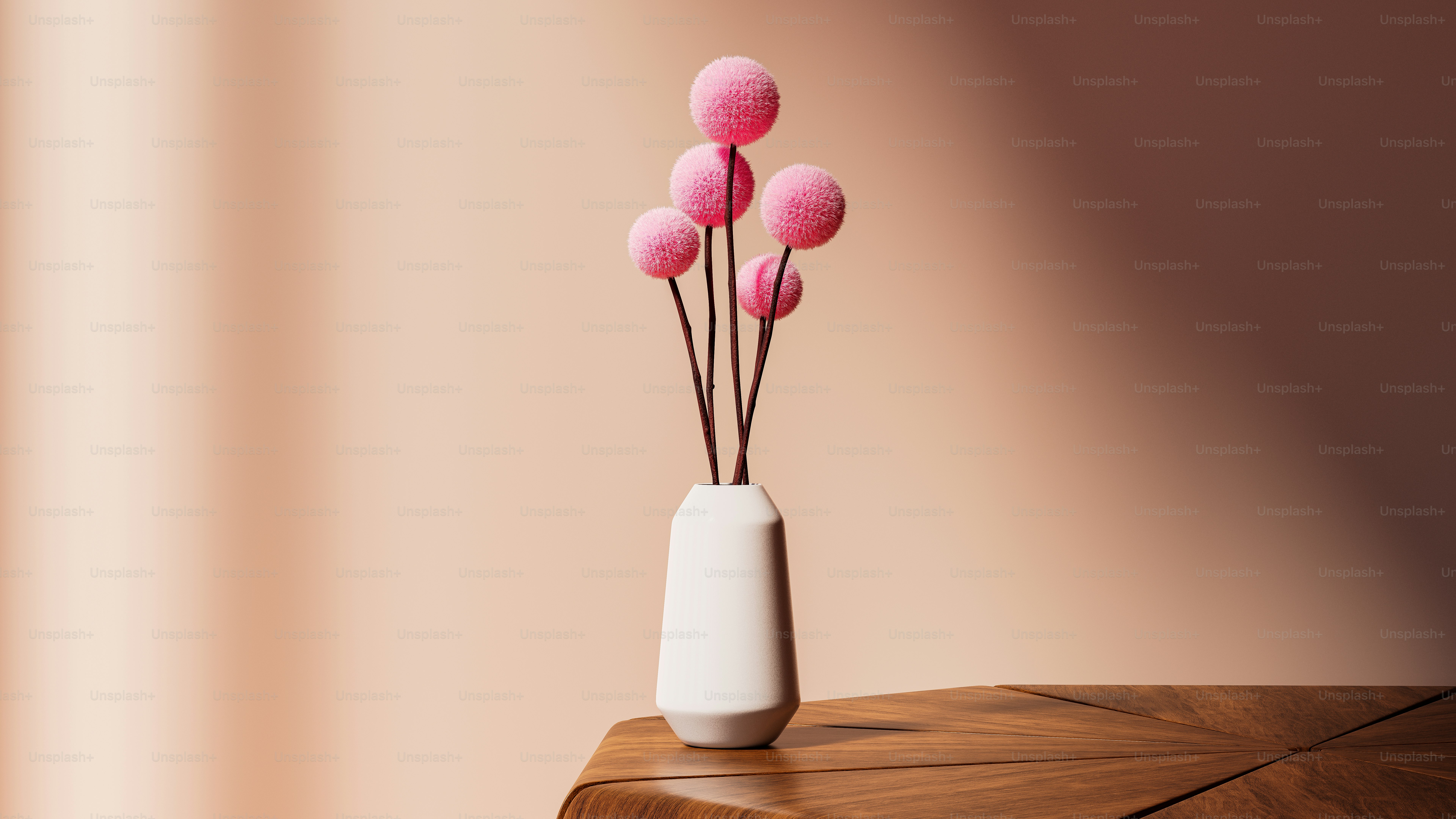 a white vase filled with pink flowers on top of a wooden table