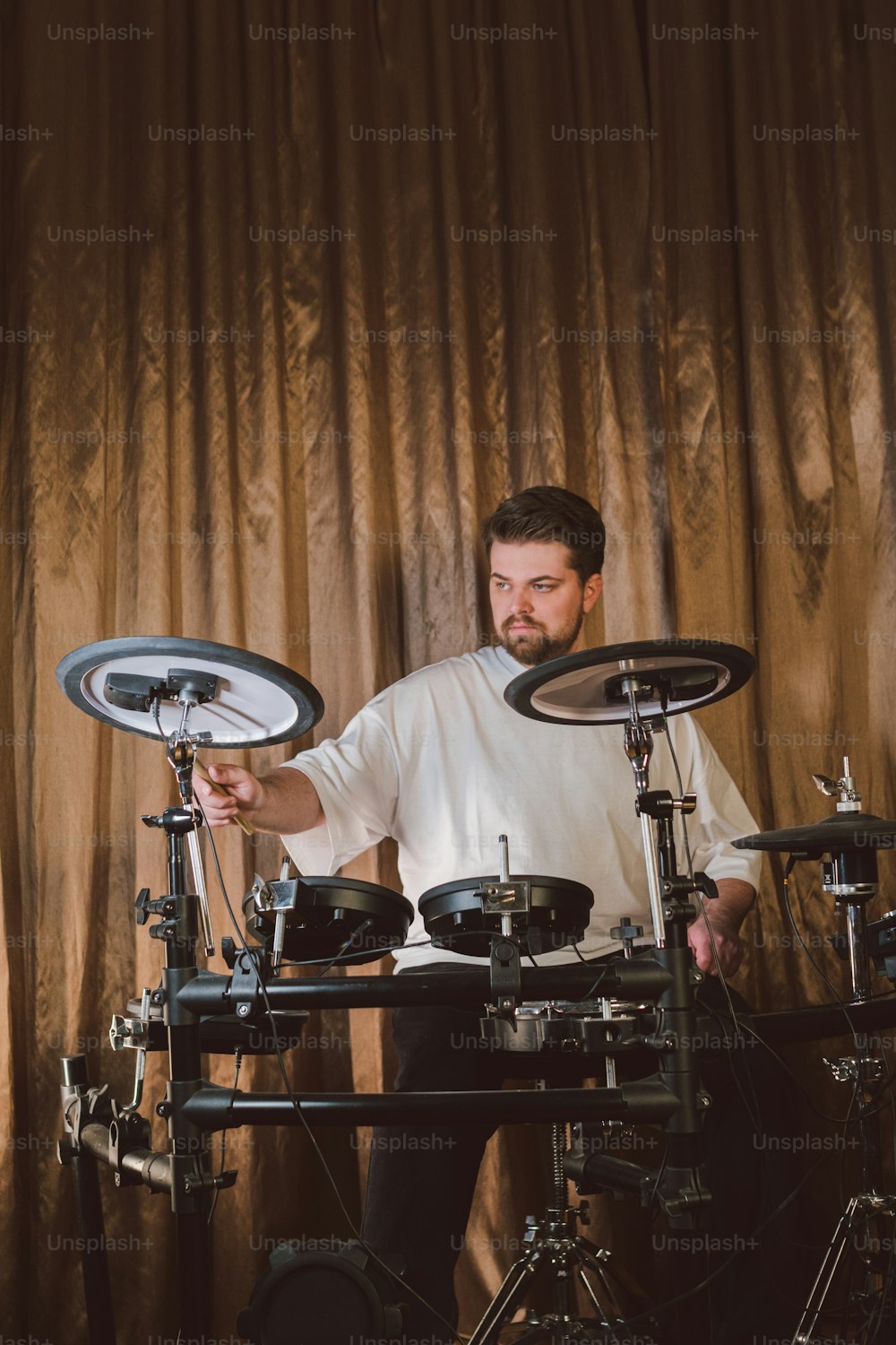 a man sitting behind a drum set in front of a curtain