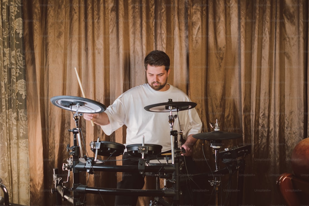 a man playing drums in front of a curtain