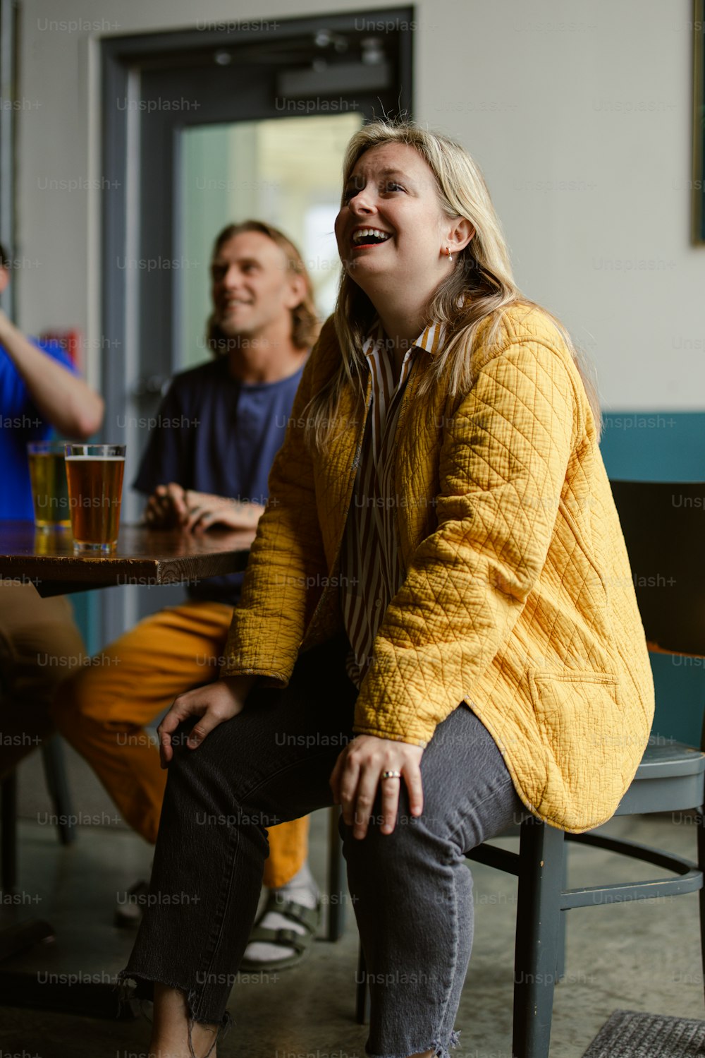 Una mujer sentada en una mesa con un vaso de cerveza