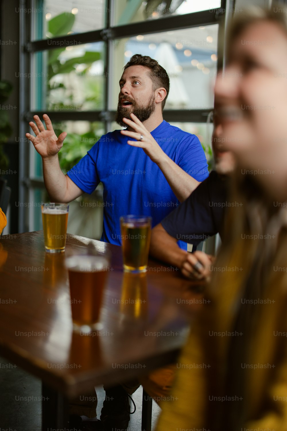 two men sitting at a table with beers in front of them