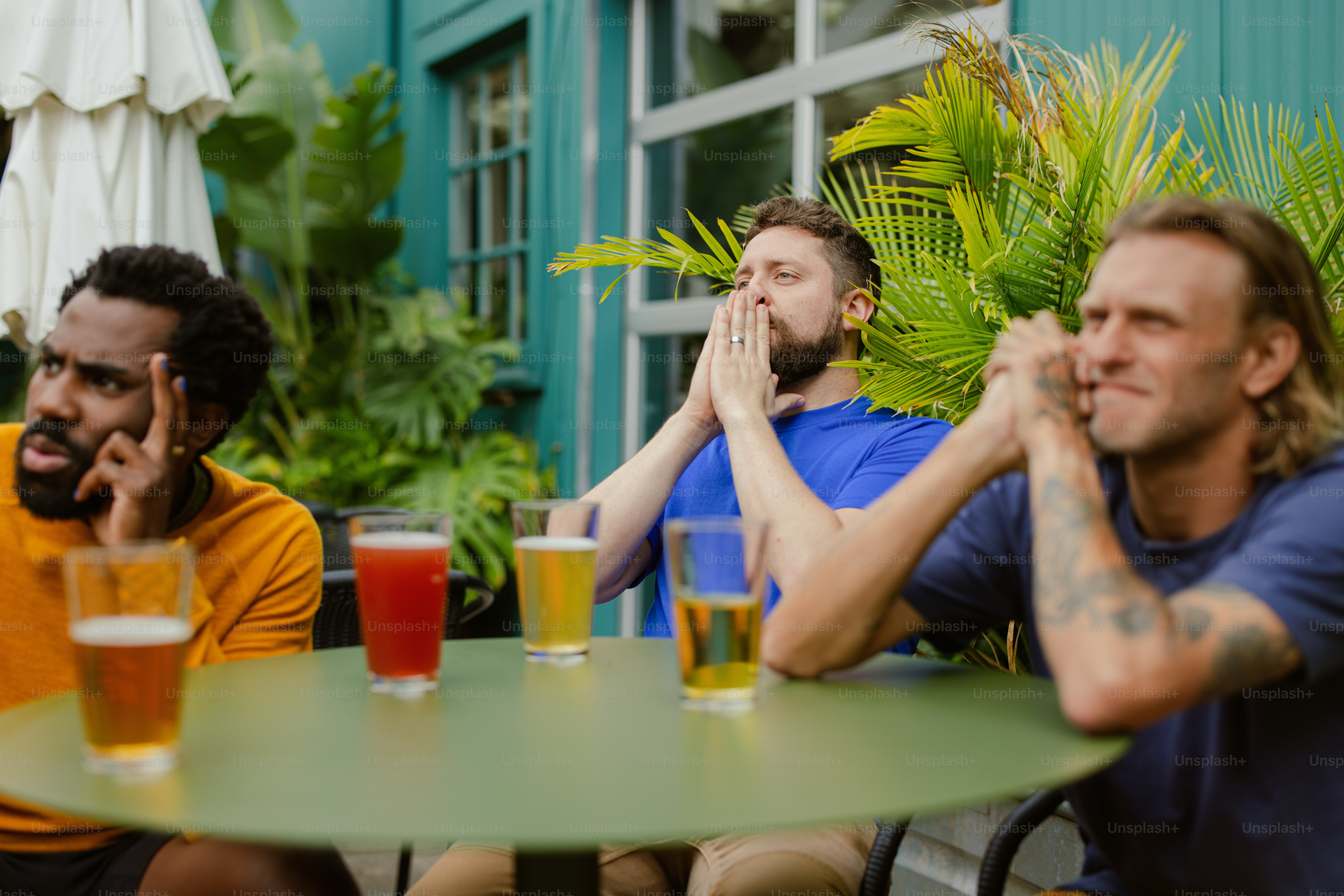 Un groupe d’hommes assis autour d’une table avec des bières