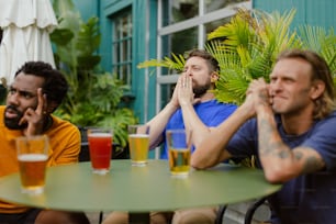 a group of men sitting around a table with beers