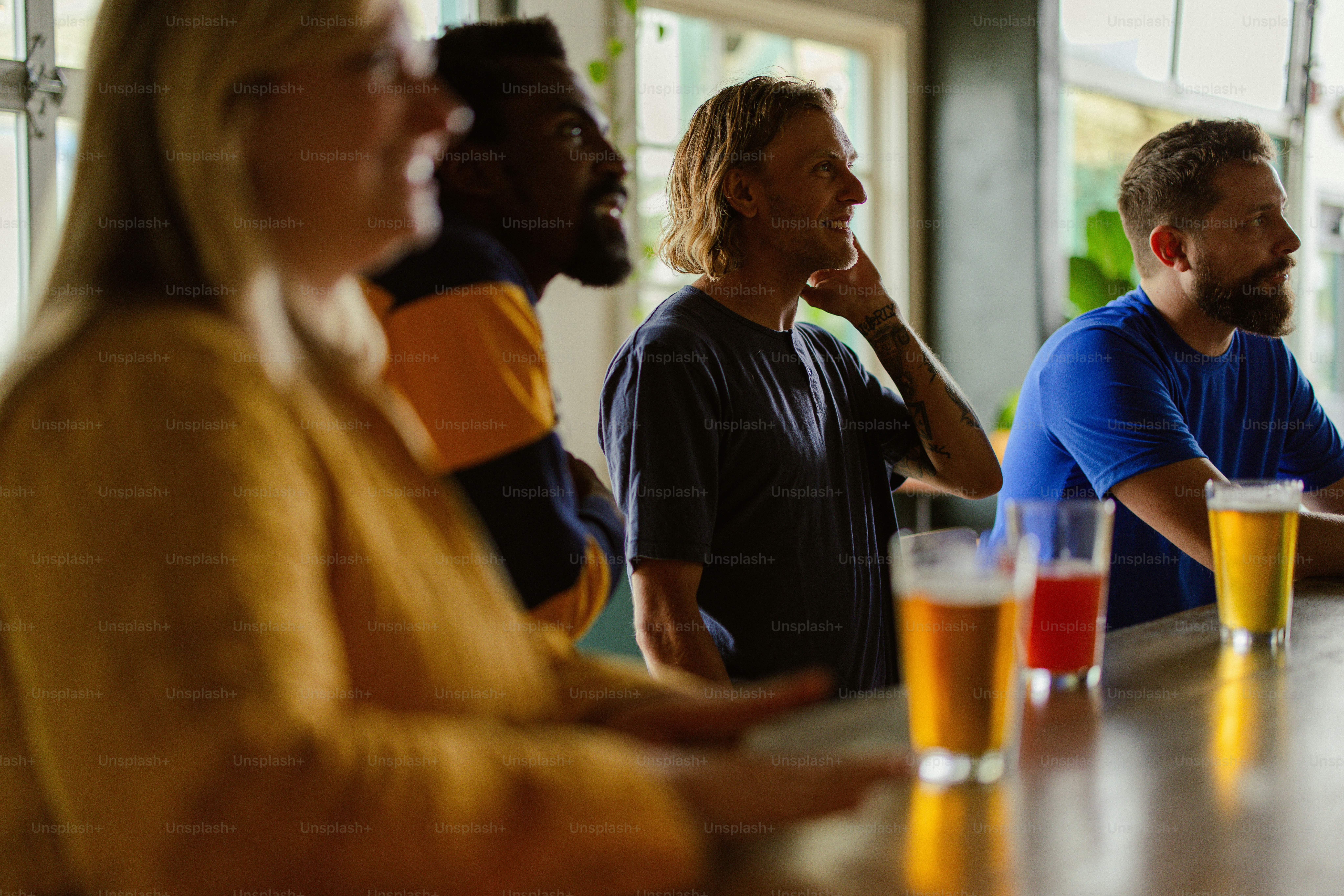 a group of people sitting at a bar with beers