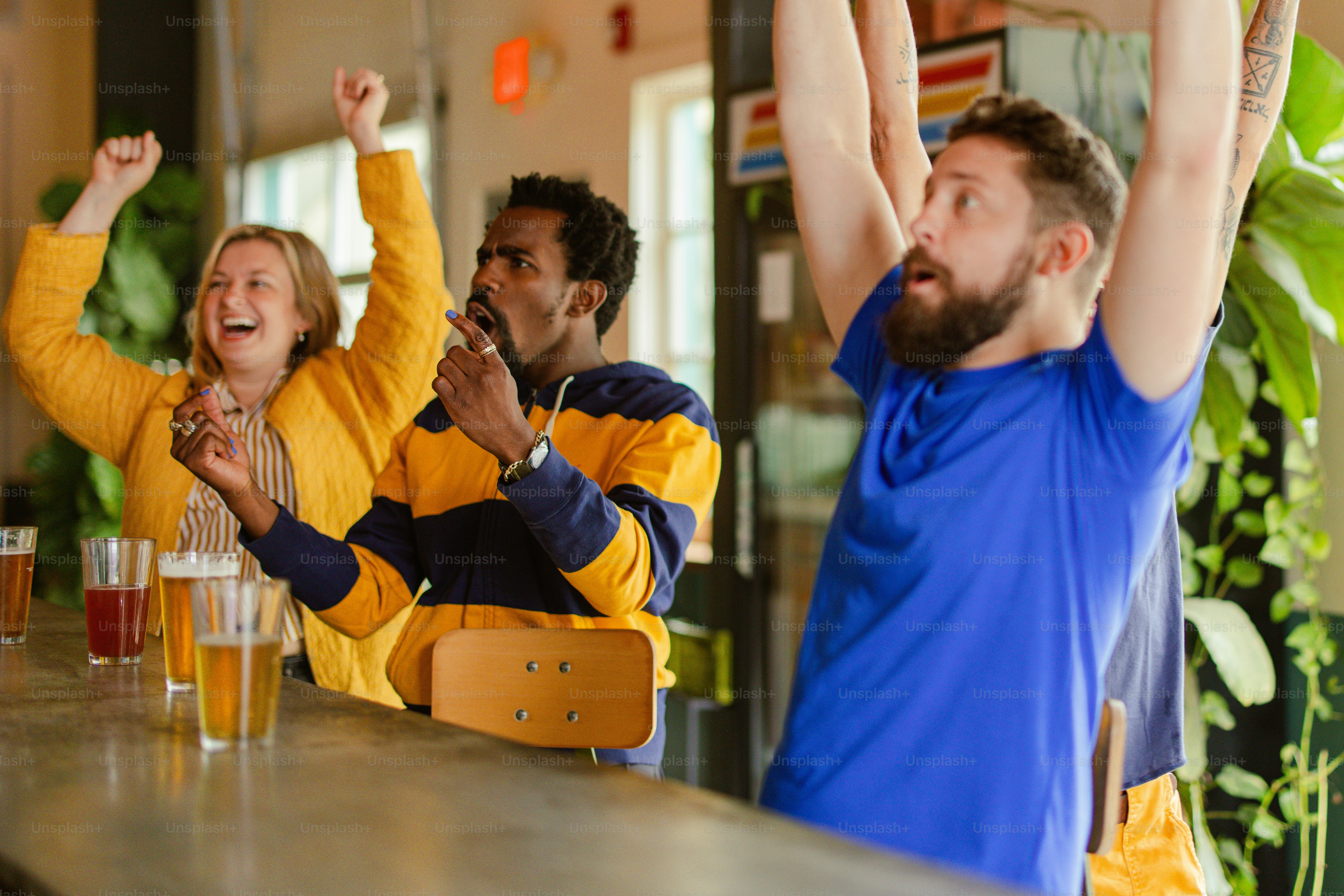 A group of people sitting at a bar raising their hands photo – Crowd ...