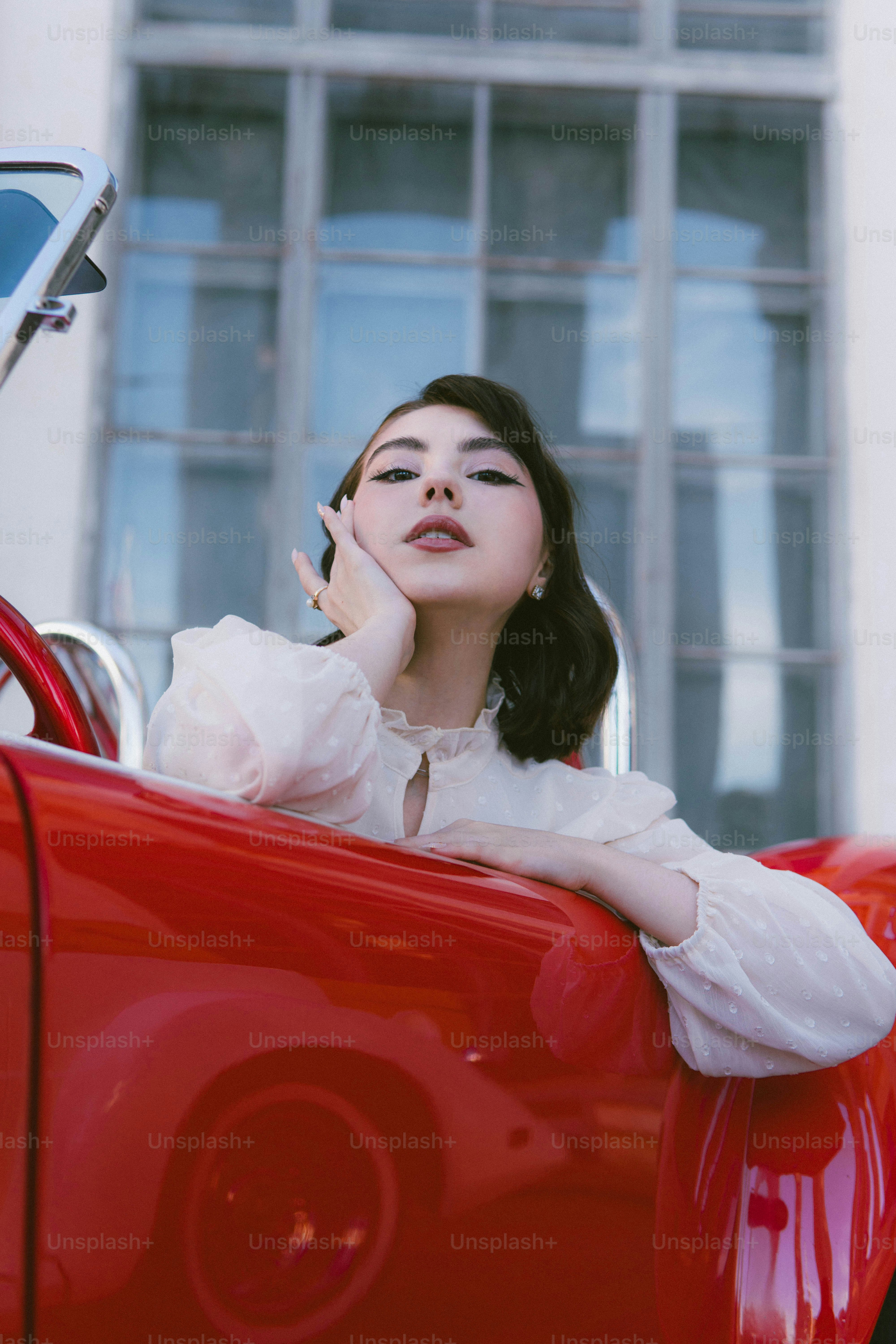 a woman sitting in the back of a red car talking on a cell phone