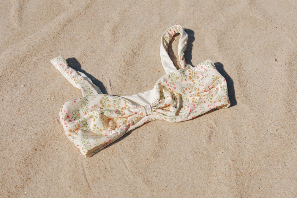 ein Bikinioberteil, das im Sand am Strand liegt