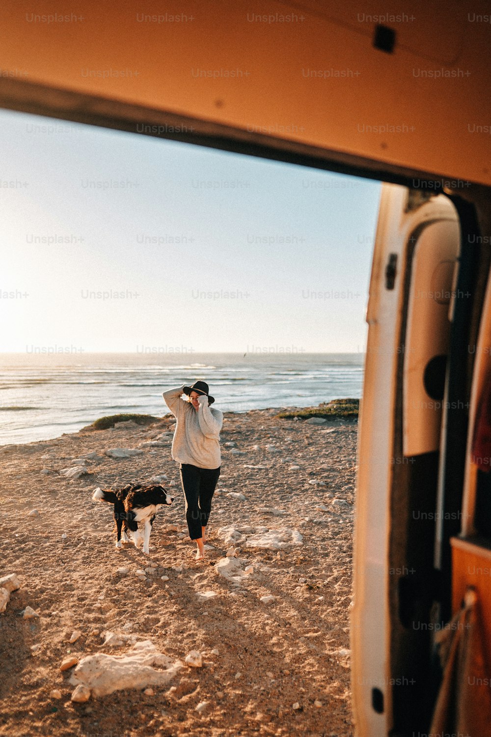 a man walking a dog on a beach next to a van