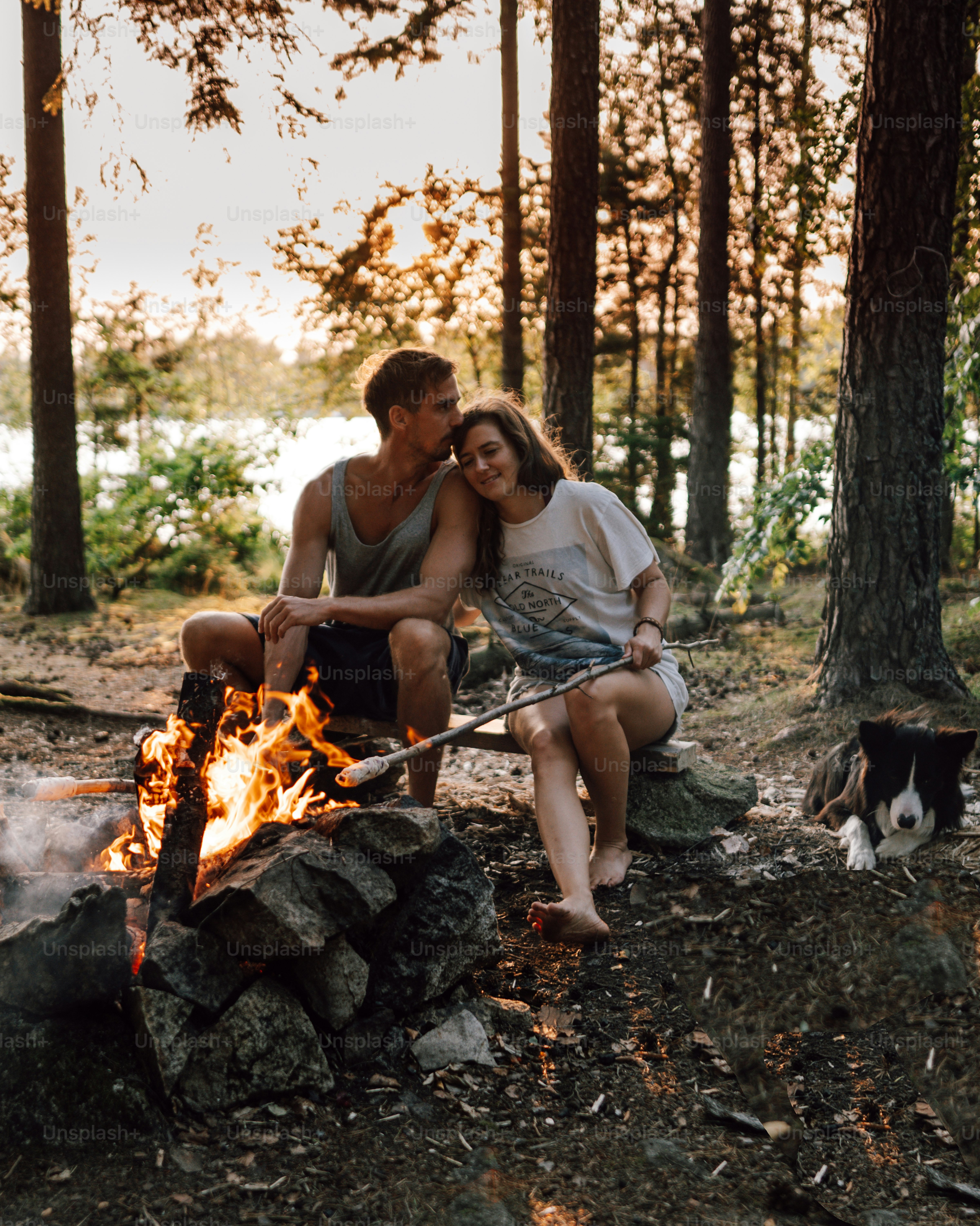 a man and a woman sitting next to a campfire