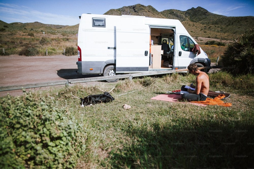 um homem sentado no chão ao lado de uma van