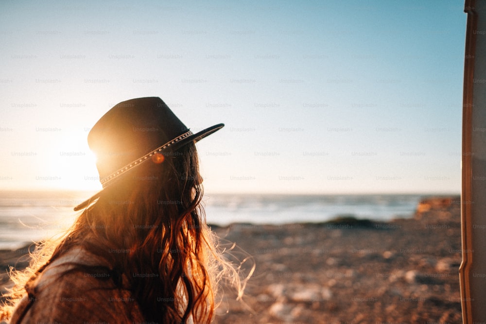una donna che indossa un cappello in piedi su una spiaggia