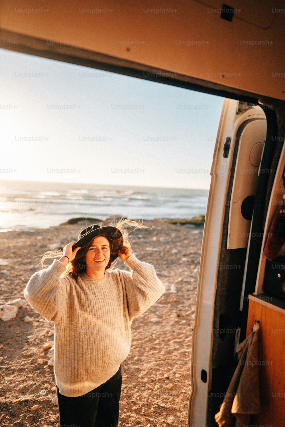 uma mulher em pé na frente de uma van em uma praia