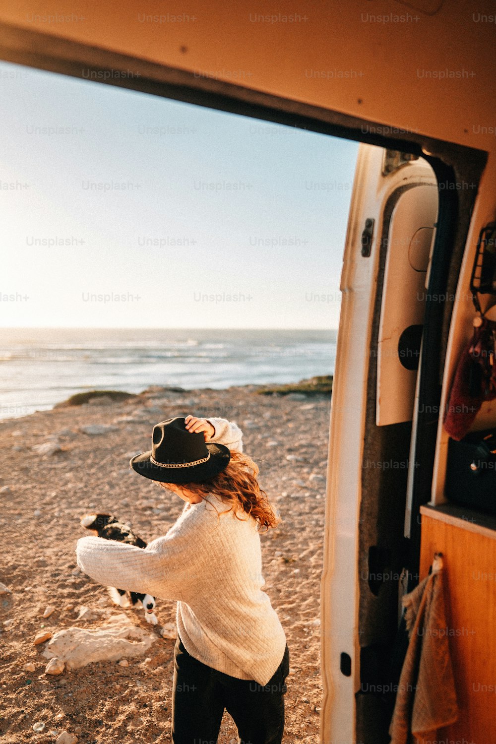 uma mulher ao lado de uma van em uma praia
