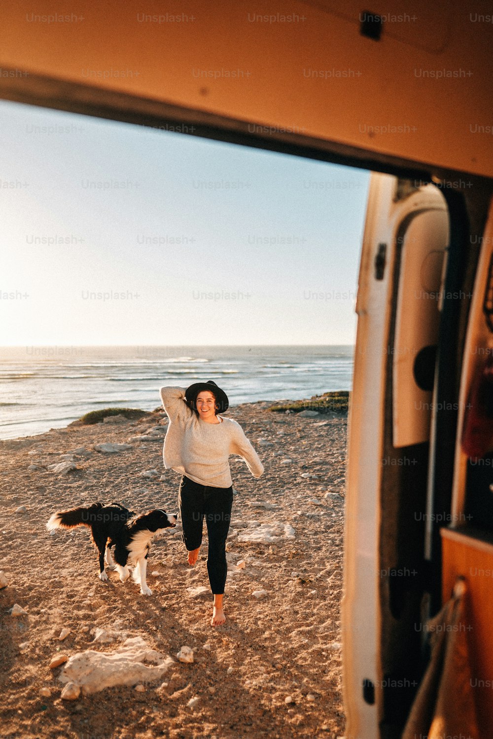 Una mujer parada junto a un perro en una playa