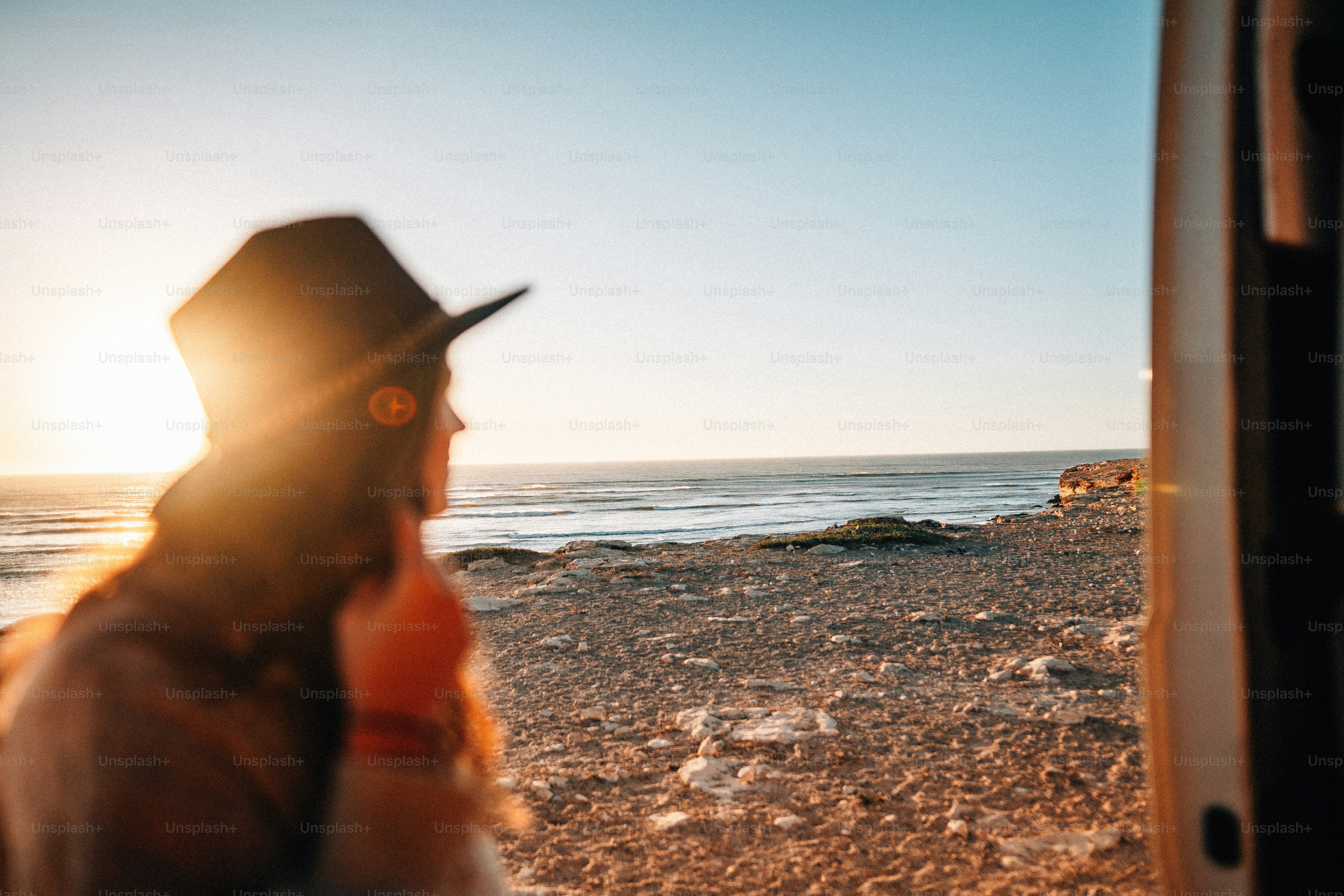 a woman wearing a hat standing next to the ocean