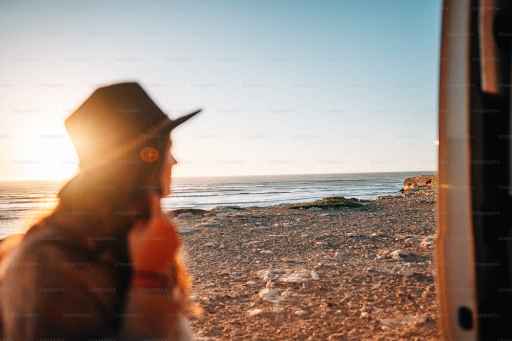 uma mulher usando um chapéu ao lado do oceano