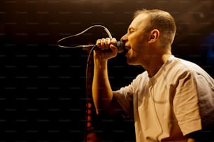 a man singing into a microphone on stage