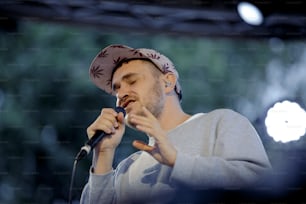 Ein Mann mit einem Kopftuch singt in ein Mikrofon