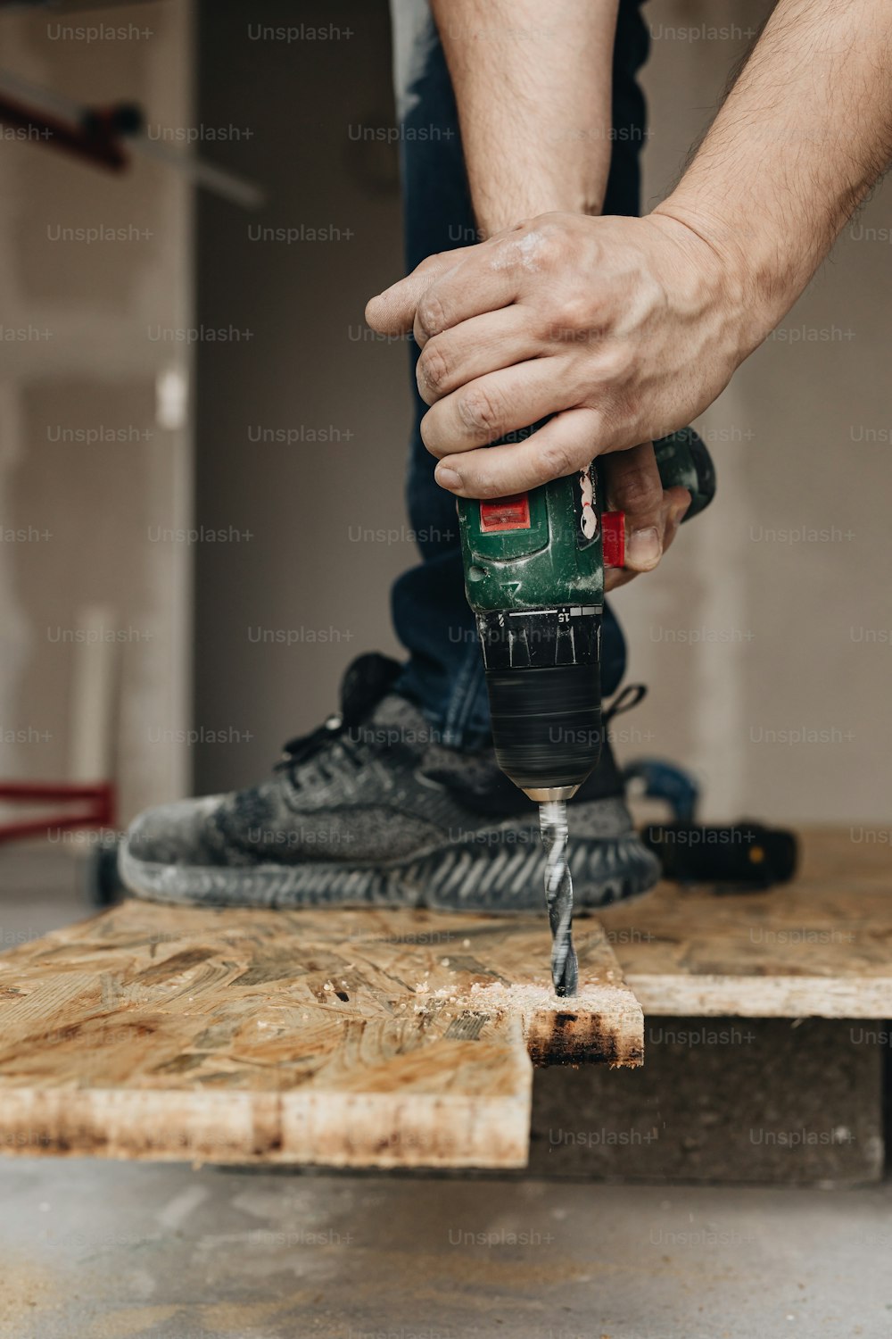 Un homme utilise une perceuse pour percer un morceau de bois