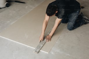 a man laying a tile on the floor
