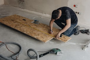 un homme travaillant sur un plancher en bois dans une pièce