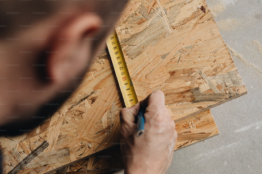 a man is measuring a piece of wood