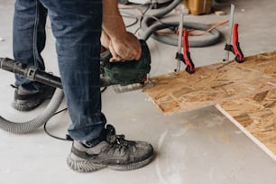 a man using a power tool on a piece of plywood