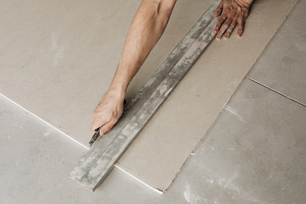 a man laying tile on the floor with a ruler