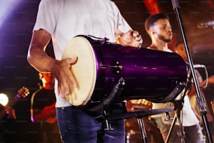 a man holding a purple drum in front of a microphone