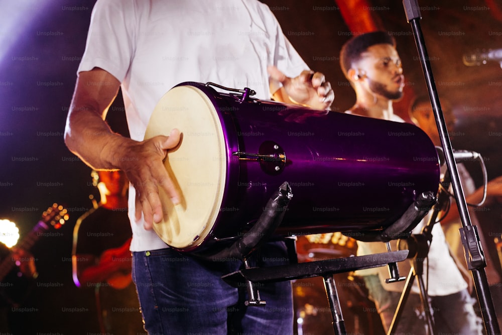 um homem segurando um tambor roxo na frente de um microfone