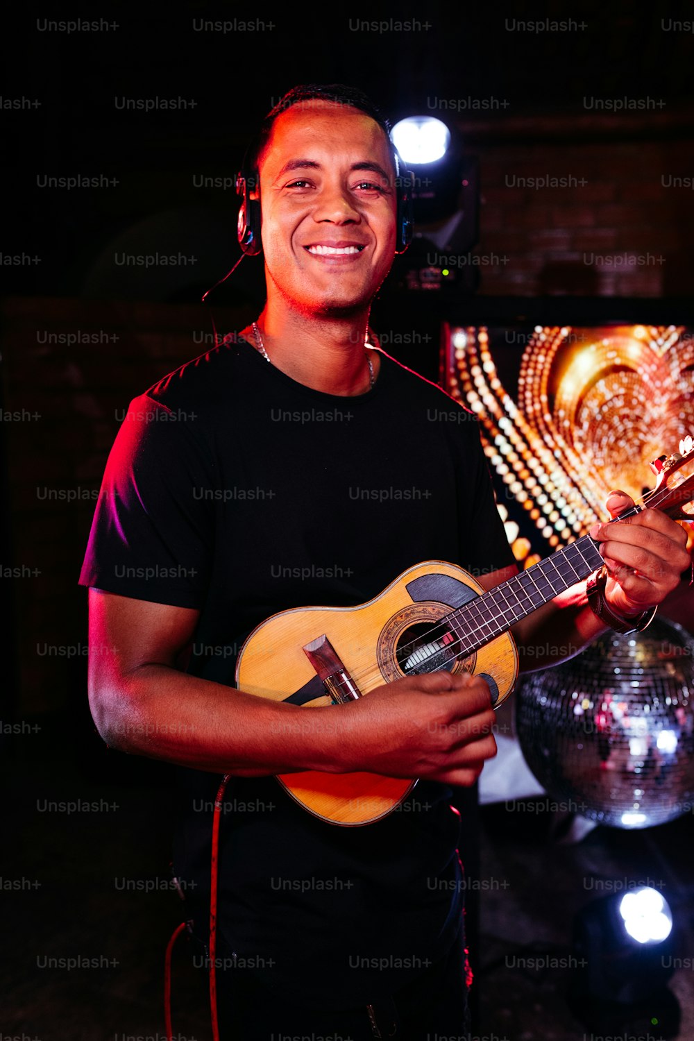a man holding a guitar in front of a disco ball
